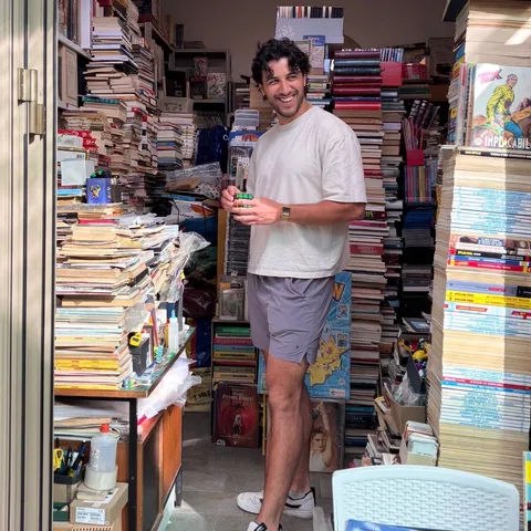 Grinning among towering stacks of books in a tiny second-hand bookshop in Italy