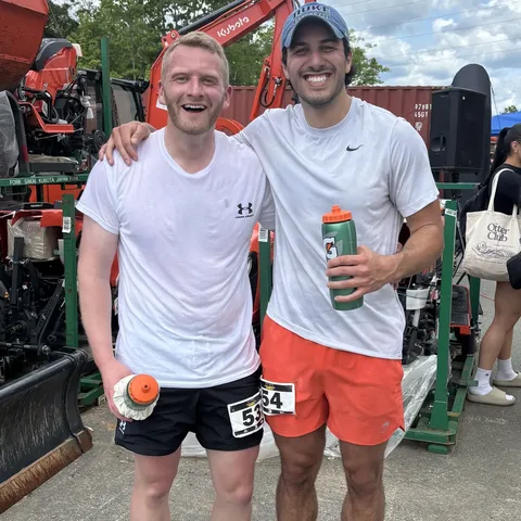 Two friends grinning after a race, wearing race bibs
