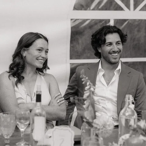 Devon and Lauren laughing together at a wedding, in black and white